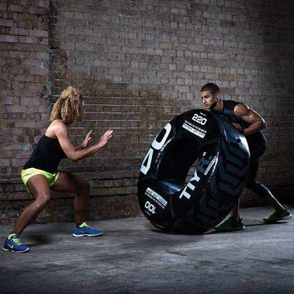 Training tyre in black with textured synthetic surface and integrated handles, shown in use; Inside Diameter 20"
